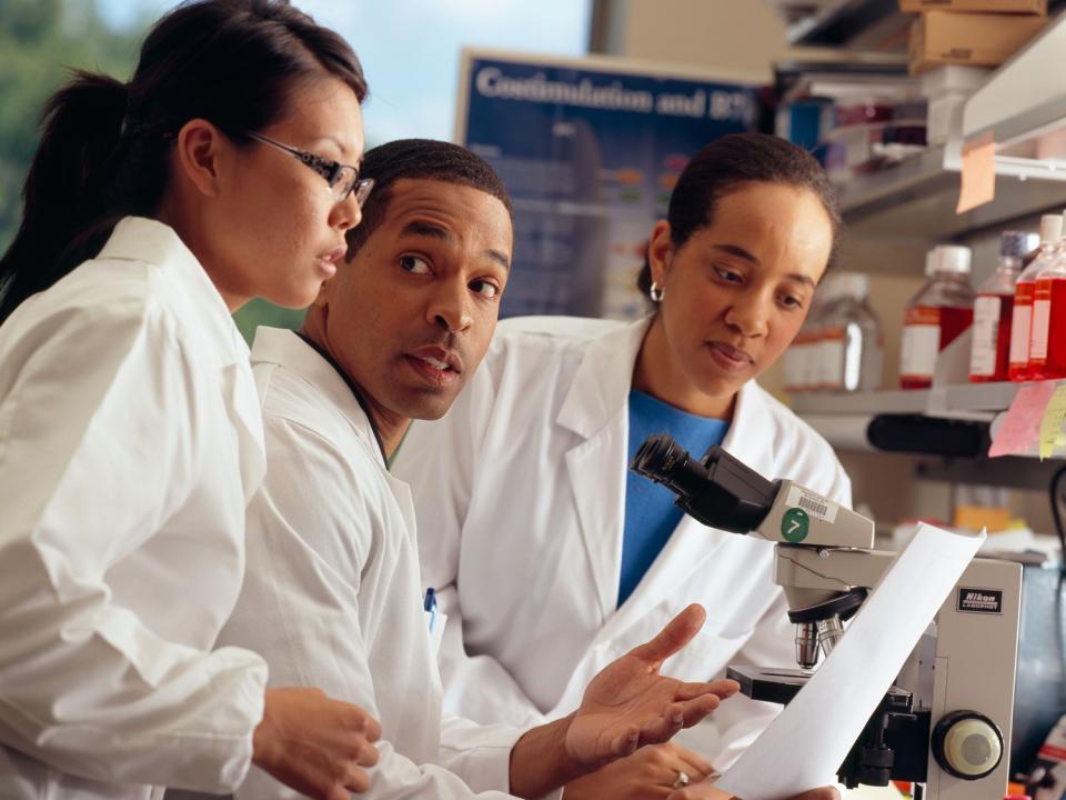 Three researchers reviewing a document.