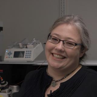 Dr. Jenkins in front of a mass spectrometer.