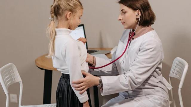 image of female physician using a stethoscope on a young female patient