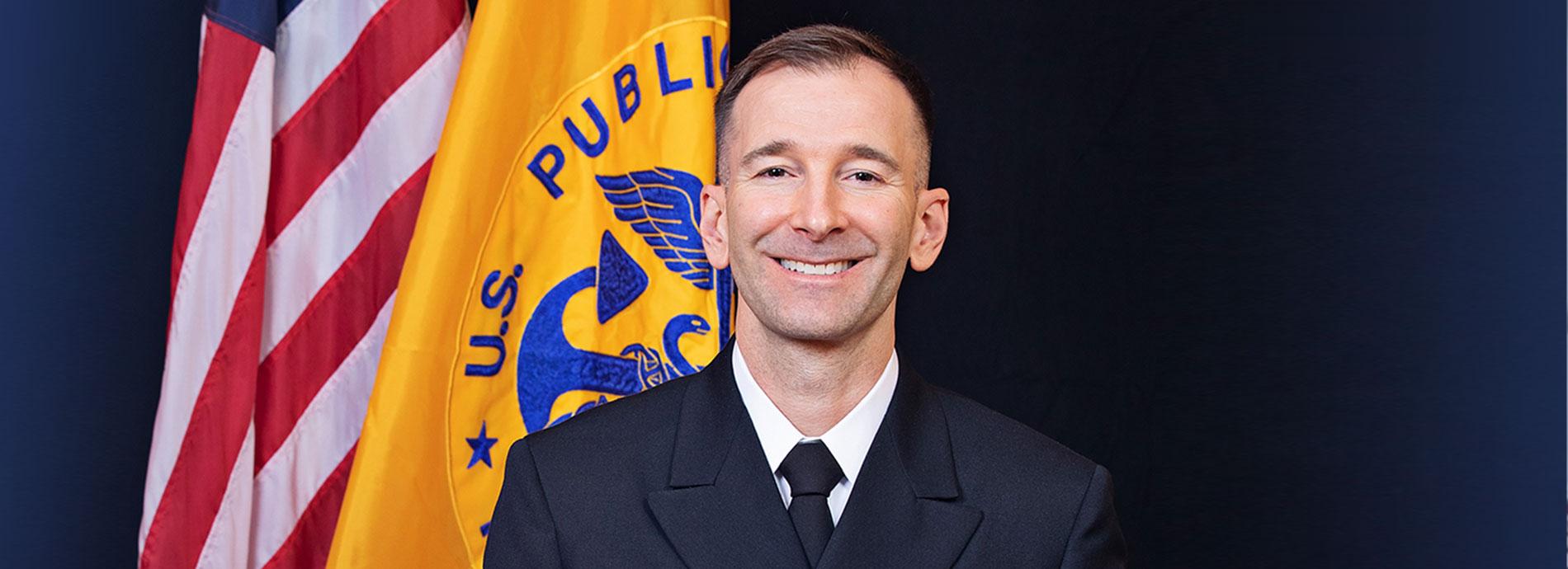 Matt Lindsley smiling in uniform next to American flag