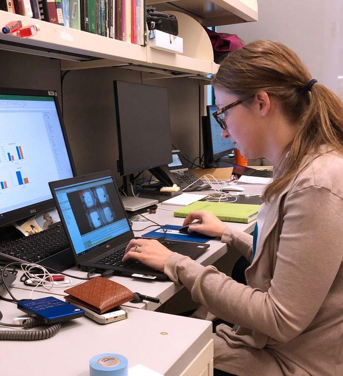 Researcher typing on a computer at her lab bench