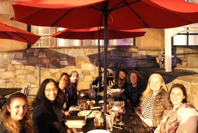 The team enjoys a meal outside under an umbrella.