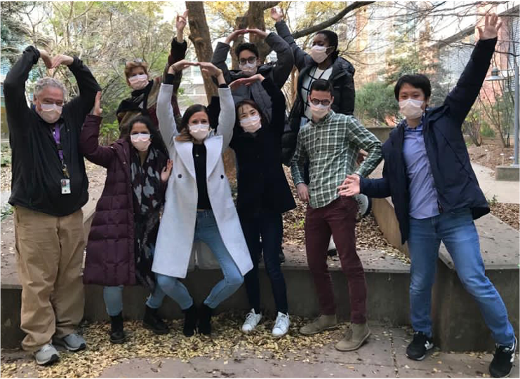 Members of the Taylor lab pose for a group photo outside in a courtyard at the NIH Clinical Center.